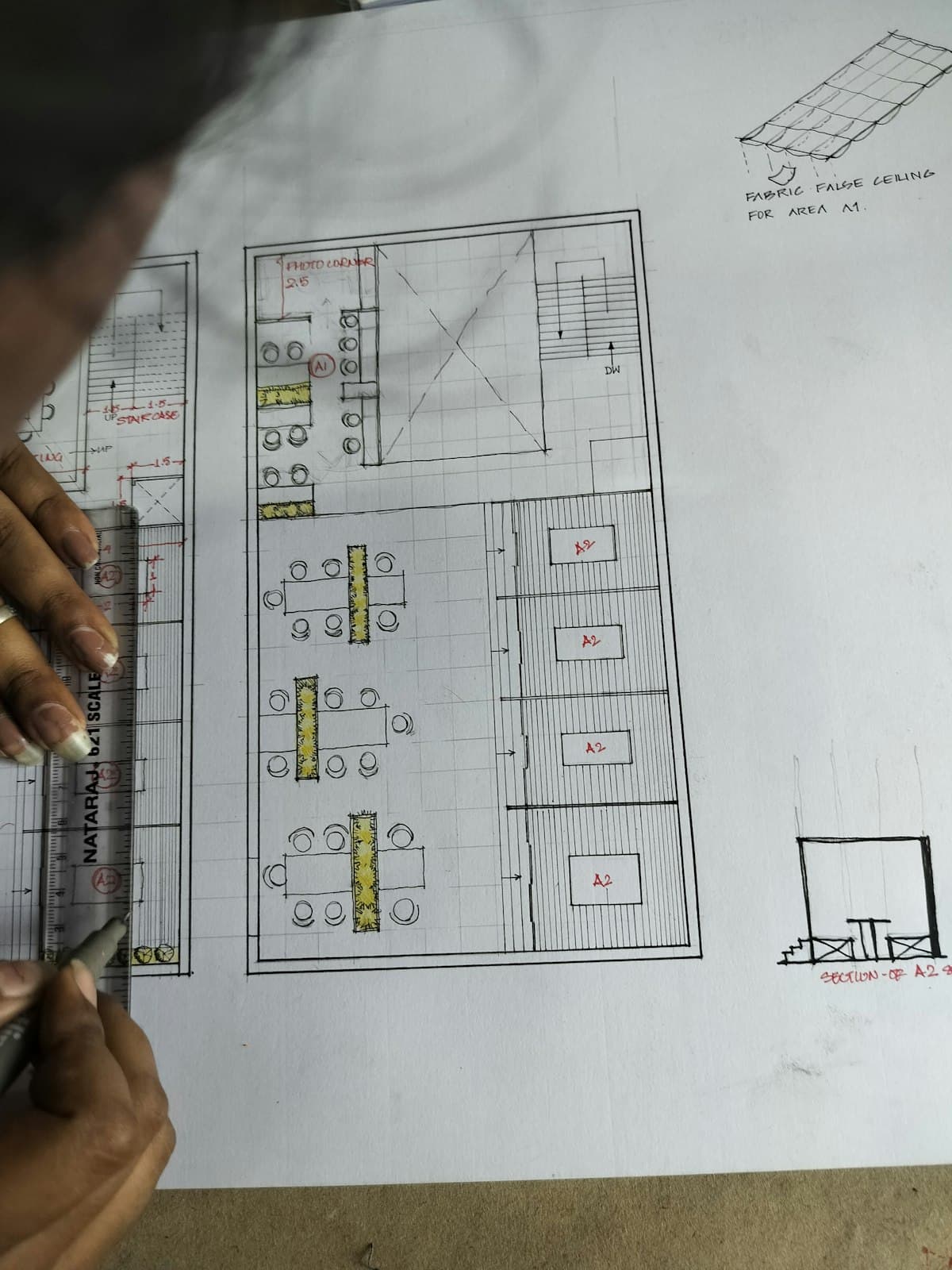 An estimator drawing out a floor plan by hand at a drafting desk